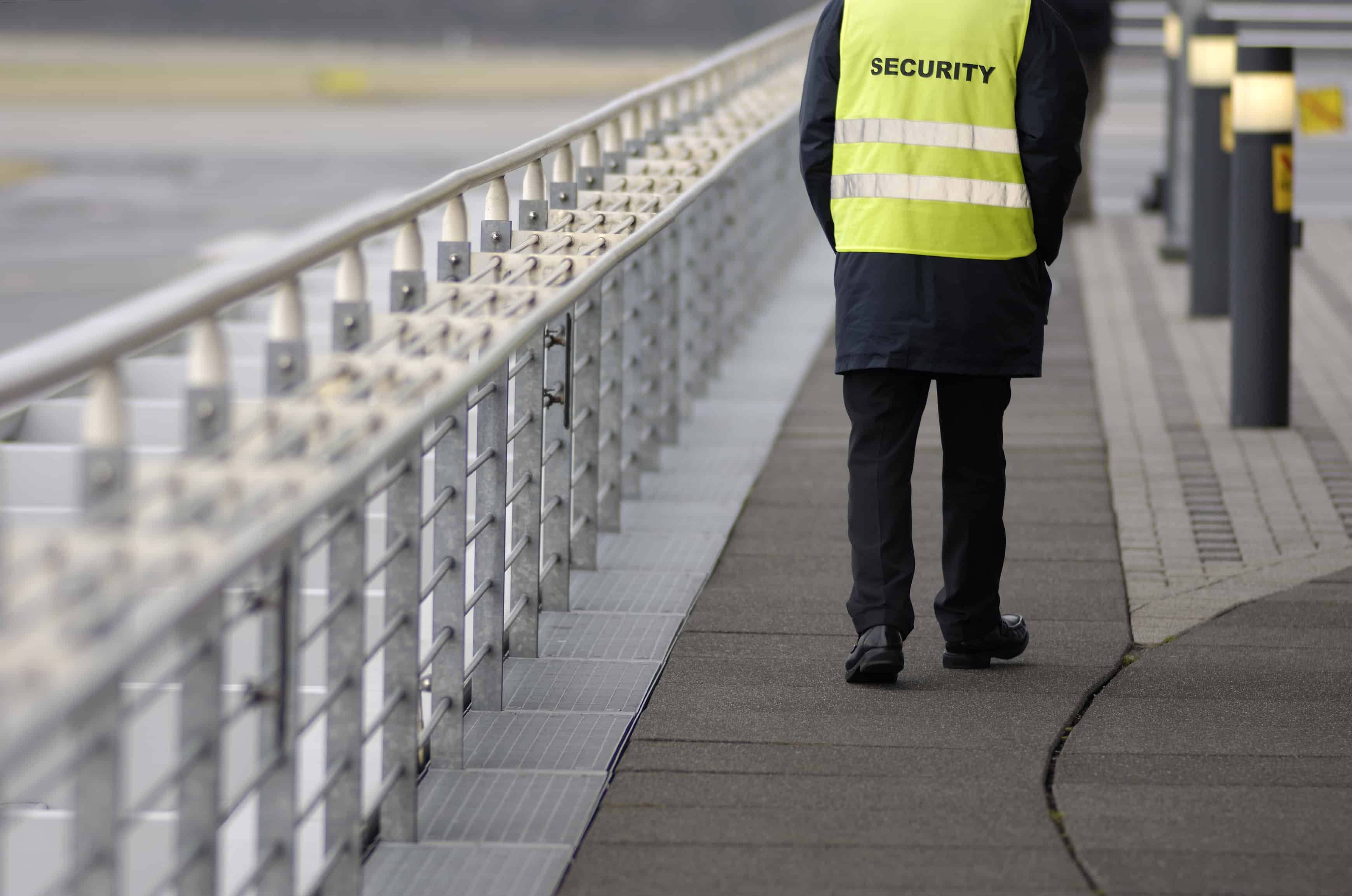 A police officer walking on a dark pavement with a shadow of his legs