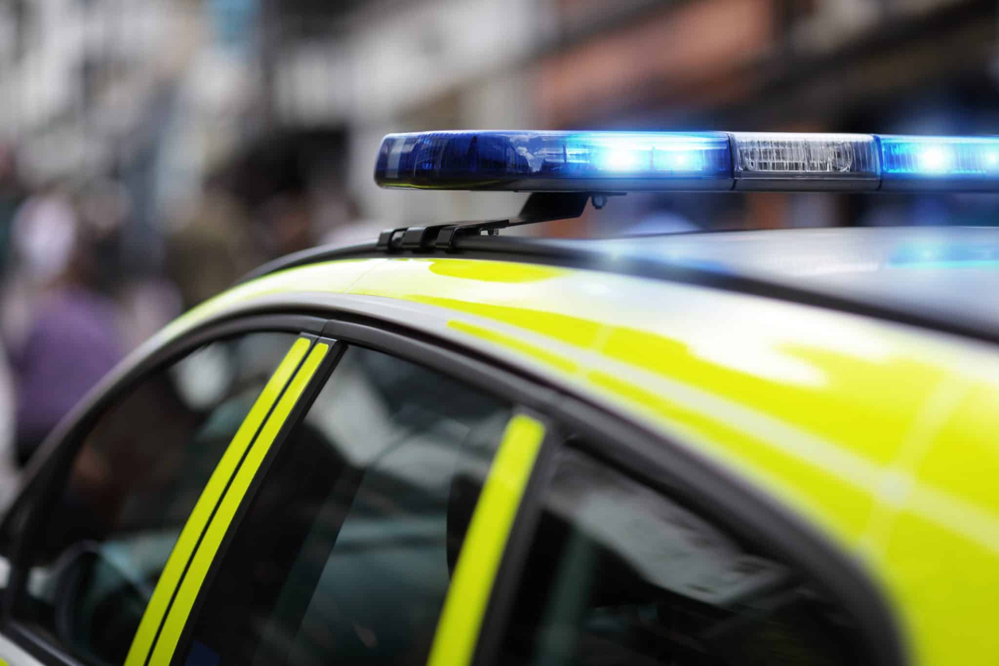 Police car with flashing blue LED lights at the scene of a crime or accident.