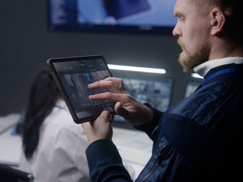 Female security officer sitting in front of a row of screens - remote security monitoring